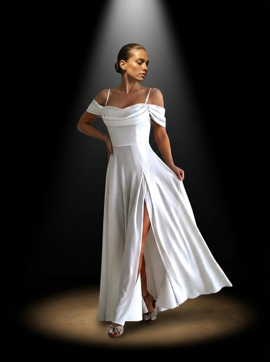 Campaign still. An ivory column gown with a draped off-the-shoulder neckline, delicate straps, a fitted waist, and a high front slit, lit by a single followspot.